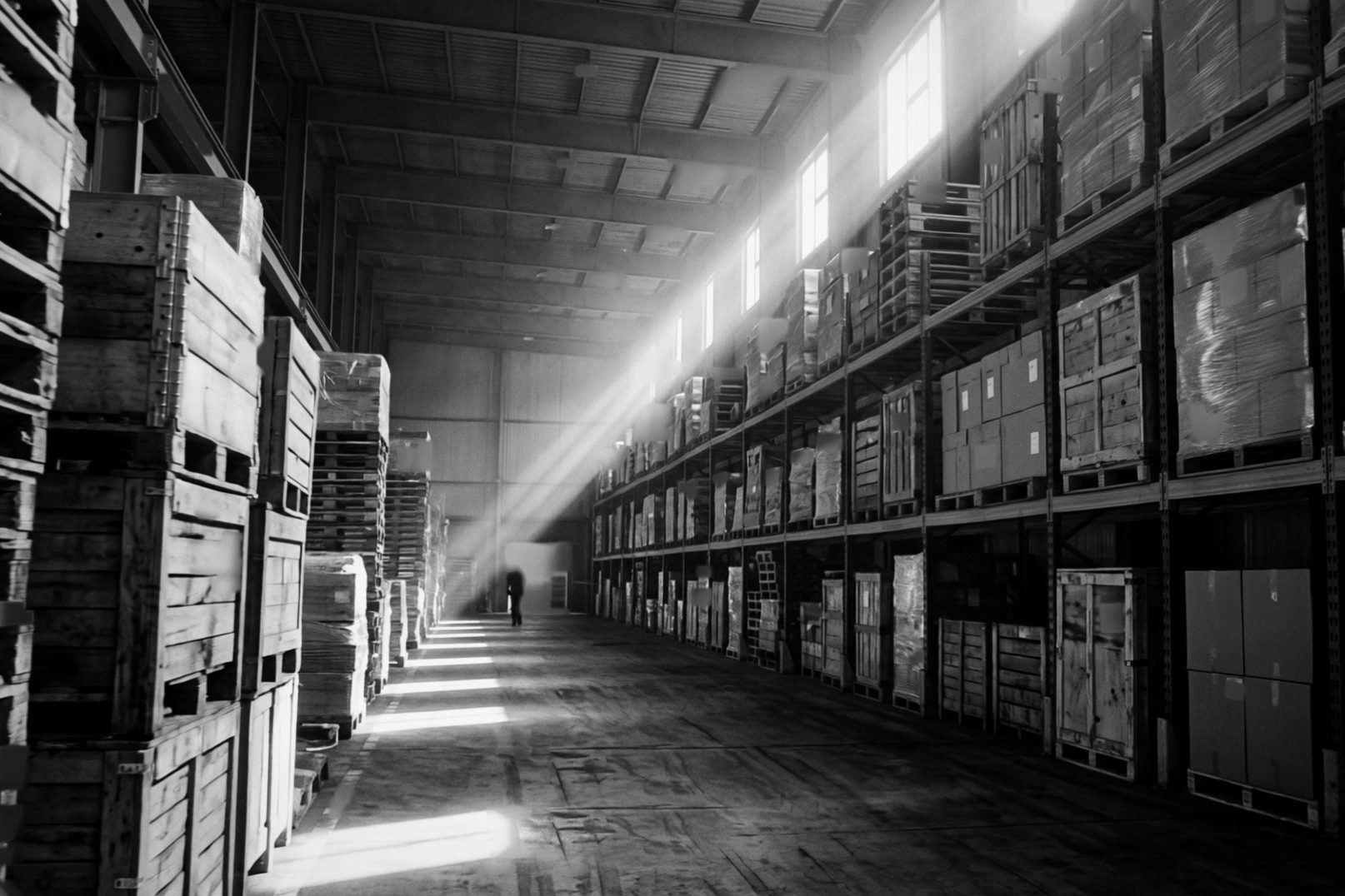 A long provisions store with shelves of crates and wrapped pallets.