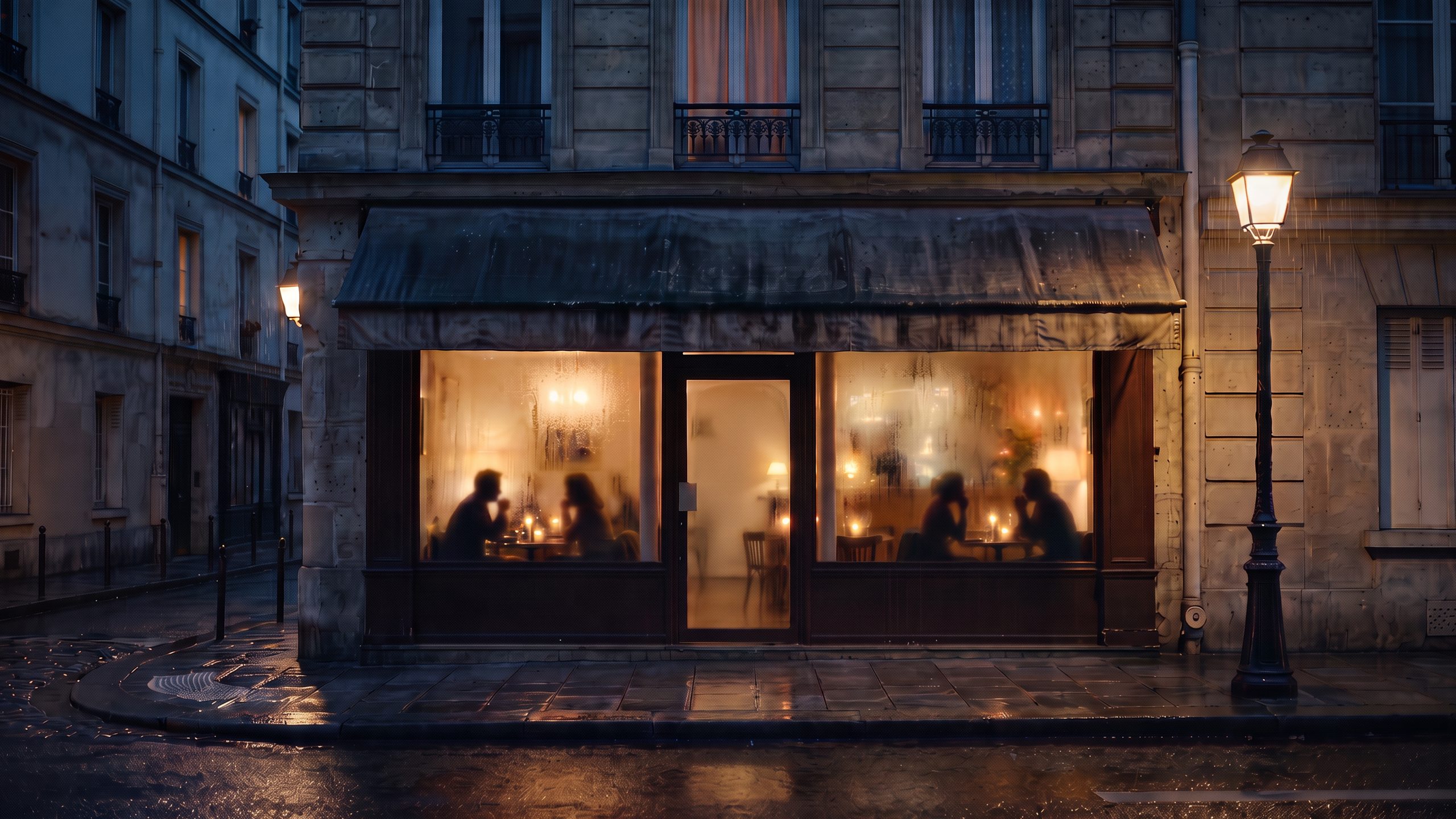 A small corner bistro on a rainy evening, with candles on its tables for two.