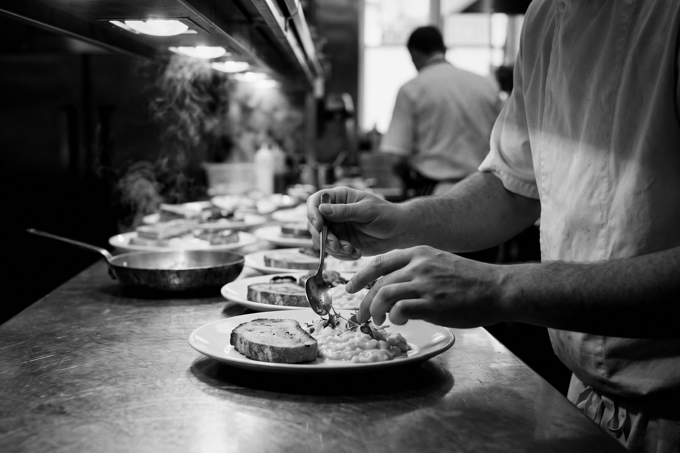A cook plates scrambled eggs and toast at the pass of a hotel kitchen.